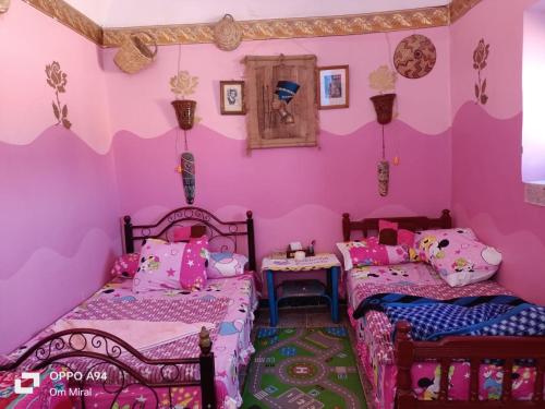 Duas camas num quarto com paredes cor-de-rosa em Arafa Nubian Guest house em Aswan