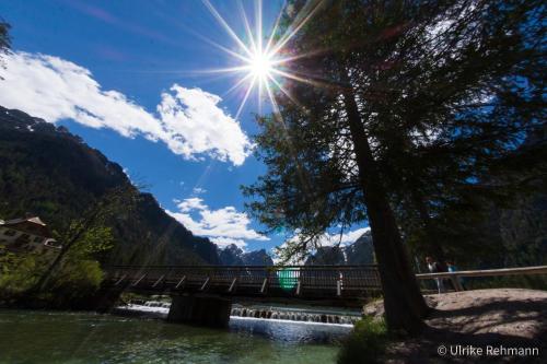 a bridge over a river with the sun in the sky at Appartment Lanz in Dobbiaco
