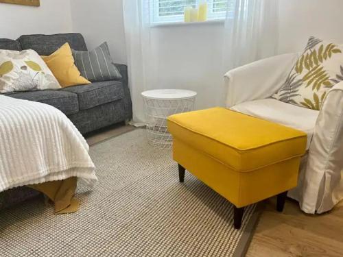 a living room with a couch and a yellow ottoman at Pass the Keys Cosy One Bedroom House with Parking in Borehamwood
