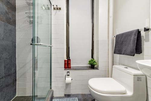 a bathroom with a toilet and a glass shower at Explore the Authentic Designers 2BD Apartment in Hudson Yards in New York