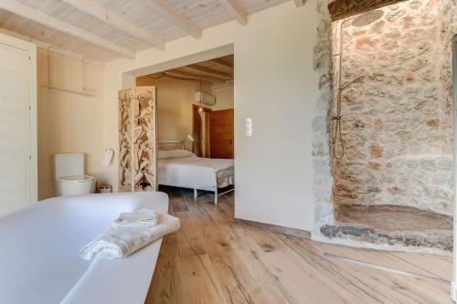 a bathroom with a tub and a room with a stone wall at Villa Petit Bijoux by Rentallorca in Can Picafort