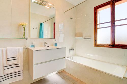 een badkamer met een wastafel, een bad en een spiegel bij Villa Can Siulet by Rentallorca in Alcudia