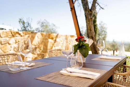 a table with wine glasses and a vase with a red flower at Pensieri di Cavatina in Castelnuovo Berardenga