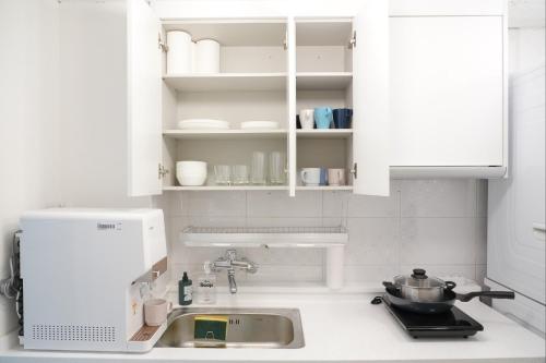 a kitchen with white cabinets and a sink at Coco Stay in Seoul