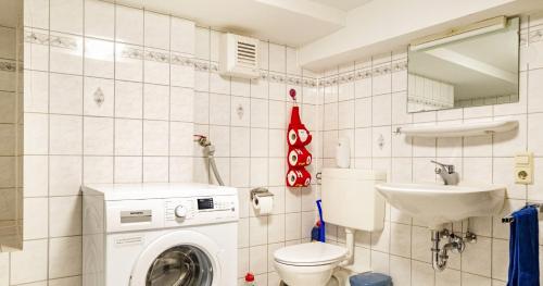 a bathroom with a washing machine and a sink at Fewo Roturach 