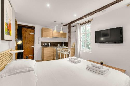 Cet appartement comprend une chambre avec un lit blanc et une cuisine. dans l'établissement Le Studio des Antiquaires - Studio climatisé, à Toulouse
