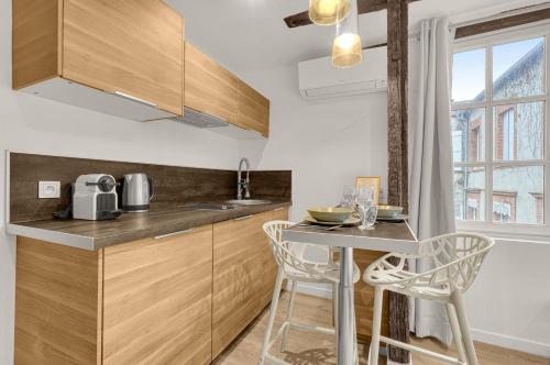 une cuisine avec une table, deux chaises et un comptoir dans l'établissement Le Studio des Antiquaires - Studio climatisé, à Toulouse