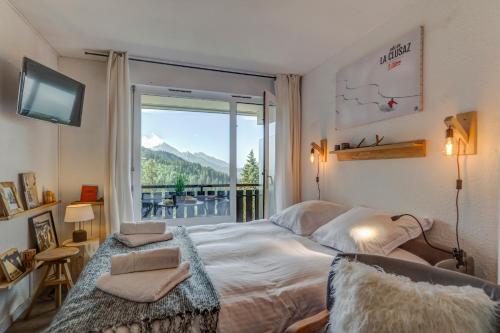 une chambre avec un lit et une grande fenêtre dans l'établissement La Maison des Bois - Avec Parking Privé, à Manigod