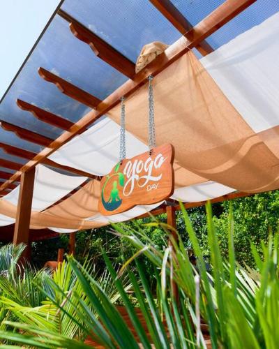 an umbrella with a sign hanging from it at Casa Iris- Home for Family, Steps From the Beach, Pool and Yoga Deck in Puerto Viejo