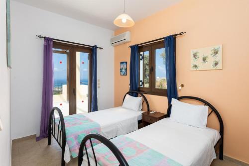 two beds in a room with two windows at Villa Spiridoula in Maroulás