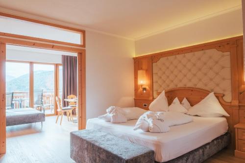 - une chambre avec un grand lit et un balcon dans l'établissement Parkhotel Holzerhof, à Maranza