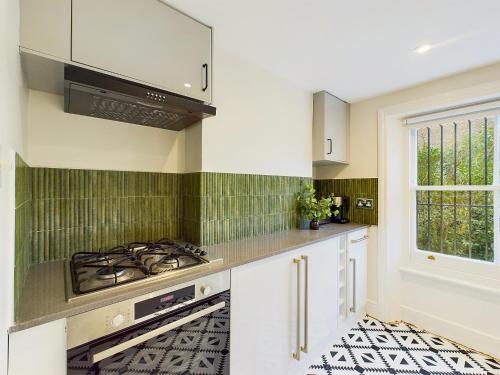 cocina con armarios blancos y fogones en Be London - Notting Hill Apartments, en Londres
