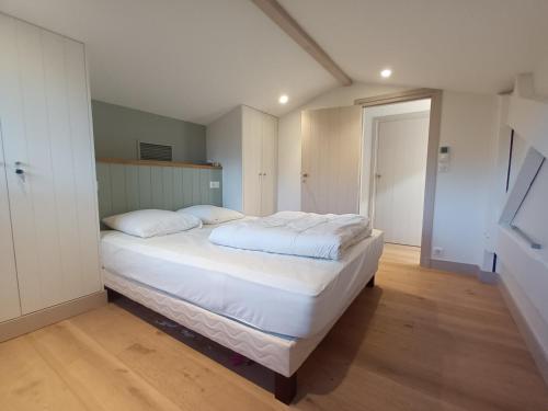 une chambre avec un grand lit avec des draps et des oreillers blancs dans l'établissement Arcachon le Moulleau maison moderne 3 chambres climatisation - 250m de la plage, à La Teste-de-Buch