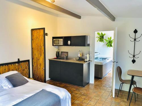 1 dormitorio con cama, escritorio y cocina en Maison D'hôtes Lagatine, en La Boissière-École