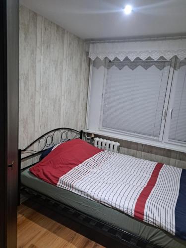 a bedroom with a bed with a red and white blanket at Apartament 3 pokoje in Słupsk