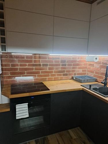 a kitchen with a counter and a brick wall at Apartament 3 pokoje in Słupsk