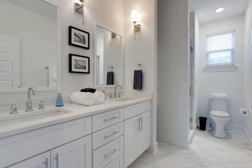 a white bathroom with two sinks and a toilet at Modern Townhome, 10min to Downtown! 8min to Grand Ole Opry! Sleeps 8! in Nashville