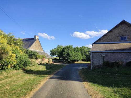 an empty road next to a house and a building at Roulotte équipée - Gite La Pâquerie in Le Louroux-Béconnais