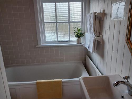 a bathroom with a tub and a sink and a window at Roberts’ Cottage in Westport
