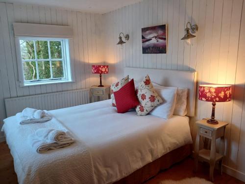 een slaapkamer met een bed met kussens en 2 lampen bij Roberts’ Cottage in Westport
