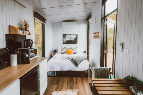 ein Schlafzimmer mit einem Bett in einem winzigen Haus in der Unterkunft River Ridge Tiny House in South Arm
