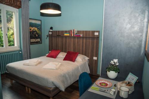 a bedroom with a bed with red pillows and a table at AL NIDO LEGAMI charme e relax in Bergamo
