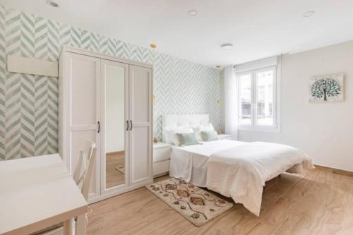 a white bedroom with a bed and a window at Apartamento El Toisón de Oro 11 Garaje gratis in Bilbao