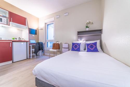 a bedroom with a large bed and a kitchen at Montempô Apparthôtel Strasbourg in Strasbourg