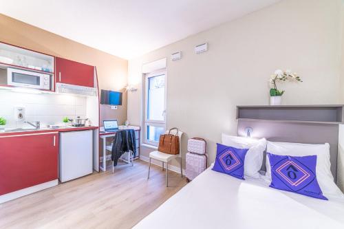 a small room with a bed and a kitchen at Montempô Apparthôtel Strasbourg in Strasbourg