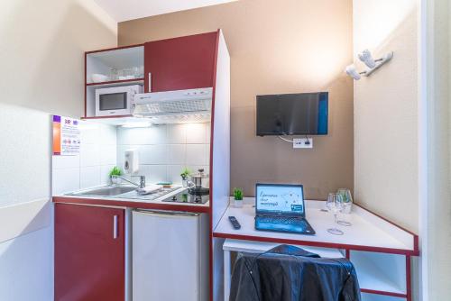 a small kitchen with a laptop computer on a counter at Montempô Apparthôtel Strasbourg in Strasbourg