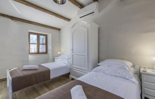 a white bedroom with two beds and a window at Heritage Villa Croc in Bibali - Haus für 4-6 Personen in Buje