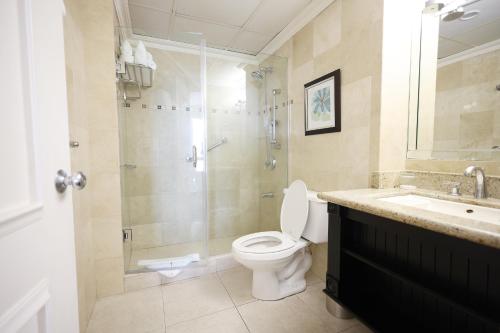 a bathroom with a toilet and a shower and a sink at Courtleigh Hotel & Suites in Kingston