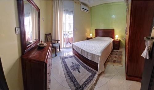 a bedroom with a bed and a dresser and a mirror at Aicha Appartement in Marrakesh