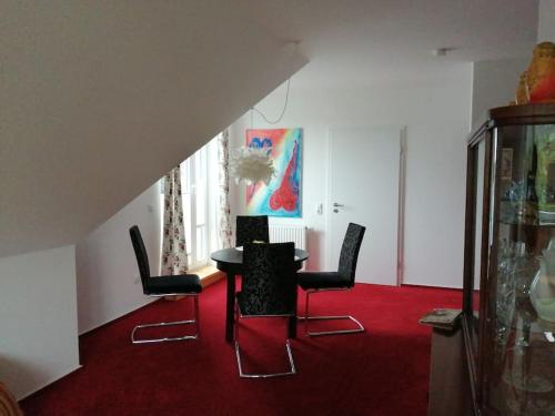 um quarto com uma mesa e cadeiras num tapete vermelho em Ferienwohnung Hude em Hude