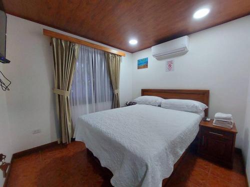a bedroom with a white bed and a window at Casa Iris - Nature Delight in Puerto Viejo