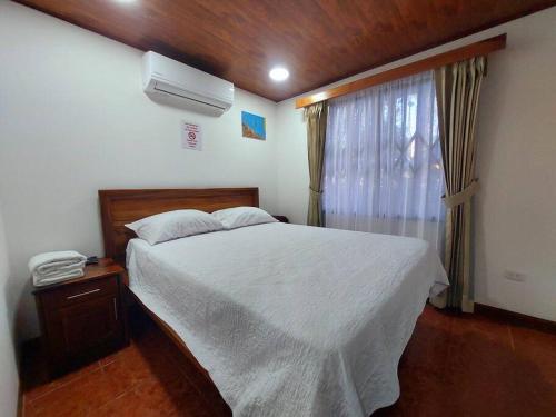 a bedroom with a white bed and a window at Casa Iris - Nature Delight in Puerto Viejo