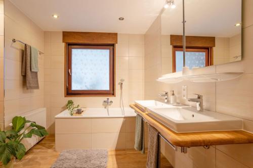een badkamer met een wastafel, een bad en een raam bij Nature Retreat Pool, Hot Tub, Sauna, Hiking-Caves in Hohenfels-Essingen