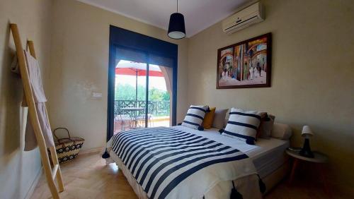 - une chambre avec un lit avec des draps rayés et une fenêtre dans l'établissement DIANA, à Marrakech