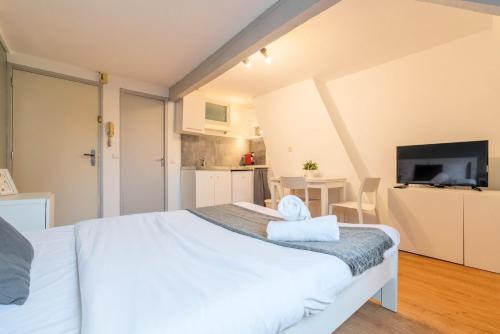 Cet appartement comprend une chambre avec un lit blanc et une cuisine. dans l'établissement Functional studio and equipped, à Lille