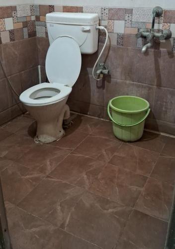 a bathroom with a toilet and a green bucket at The Grand Hospitality in Coimbatore