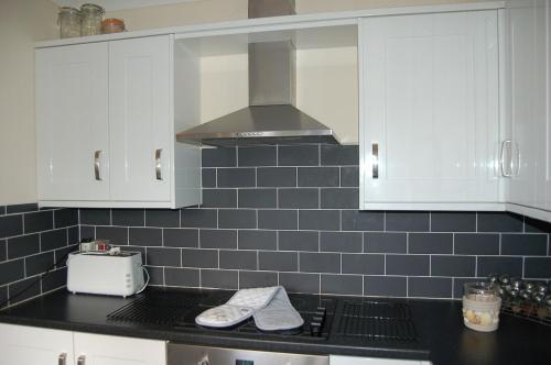 a kitchen with white cabinets and a black counter top at Ty Pen y Bryn in Dolgellau in Dolgellau