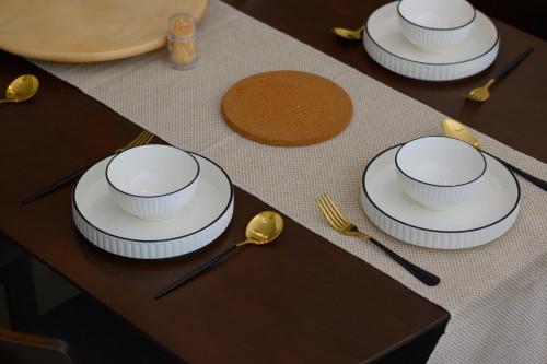 a table with white plates and gold spoons on it at Myuko Homestay (2-7 pax) 10min to BOH in Brinchang