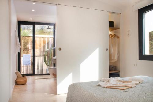 a bedroom with white walls and a bed and a balcony at YourHouse Iris House in Colonia de Sant Pere