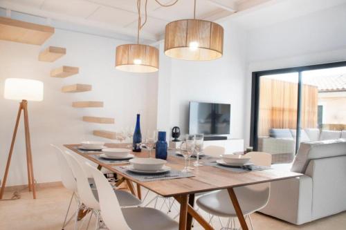 a dining room with a wooden table and white chairs at YourHouse Iris House in Colonia de Sant Pere