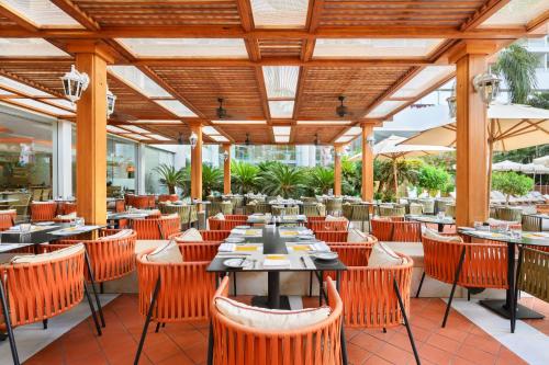 a restaurant with orange chairs and tables and umbrellas at Royal Beach Eilat by Isrotel Exclusive in Eilat