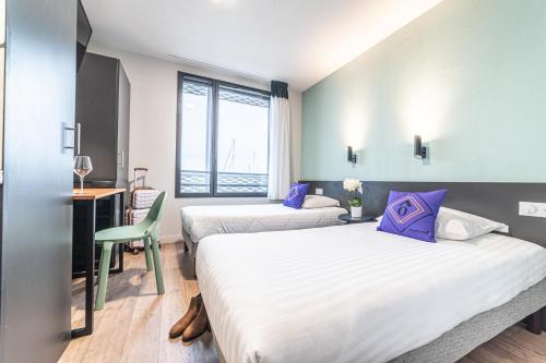 a hotel room with two beds and a desk with a chair at Montempô Bordeaux Centre - Bassins à flot in Bordeaux