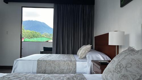 a hotel room with two beds and a window at Arenal Monara in Fortuna