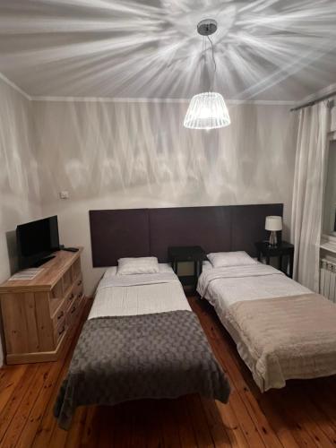 a bedroom with two beds and a chandelier at Apartament Bankowy in Olecko