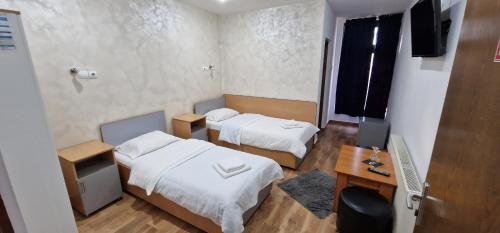 a room with two beds and a desk and a television at Pensiunea Old Sheriff in Bistriţa