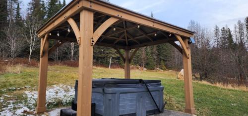 a wooden gazebo with a trash can in a field at Le Repere Etoile au coeur de la nature in Sainte-Lucie-de-Doncaster